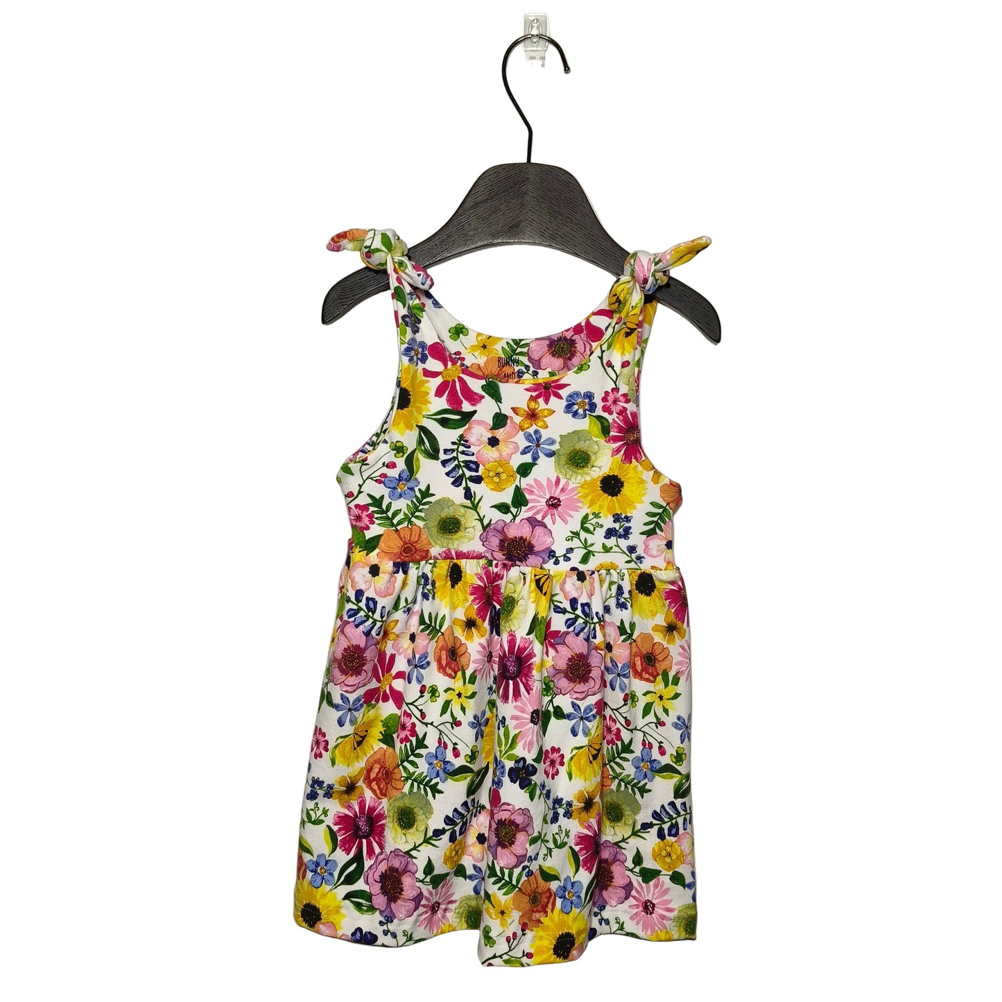 A tie strap dress for toddlers, with a colorful floral pattern, displayed on a grey hanger against a white background.