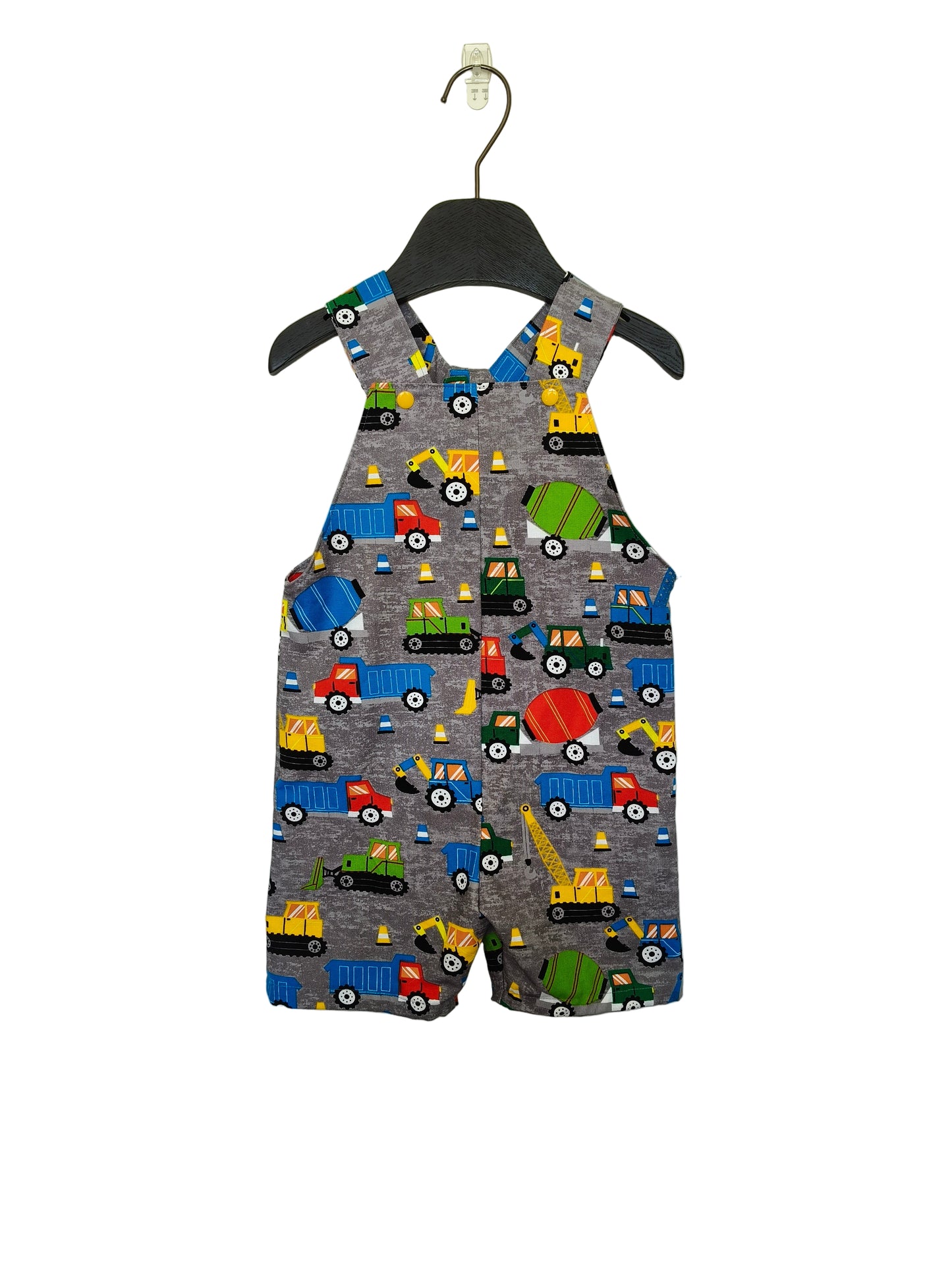 A pair of sleeveless overalls for children, featuring a construction theme with various vehicles in colors other than gray.