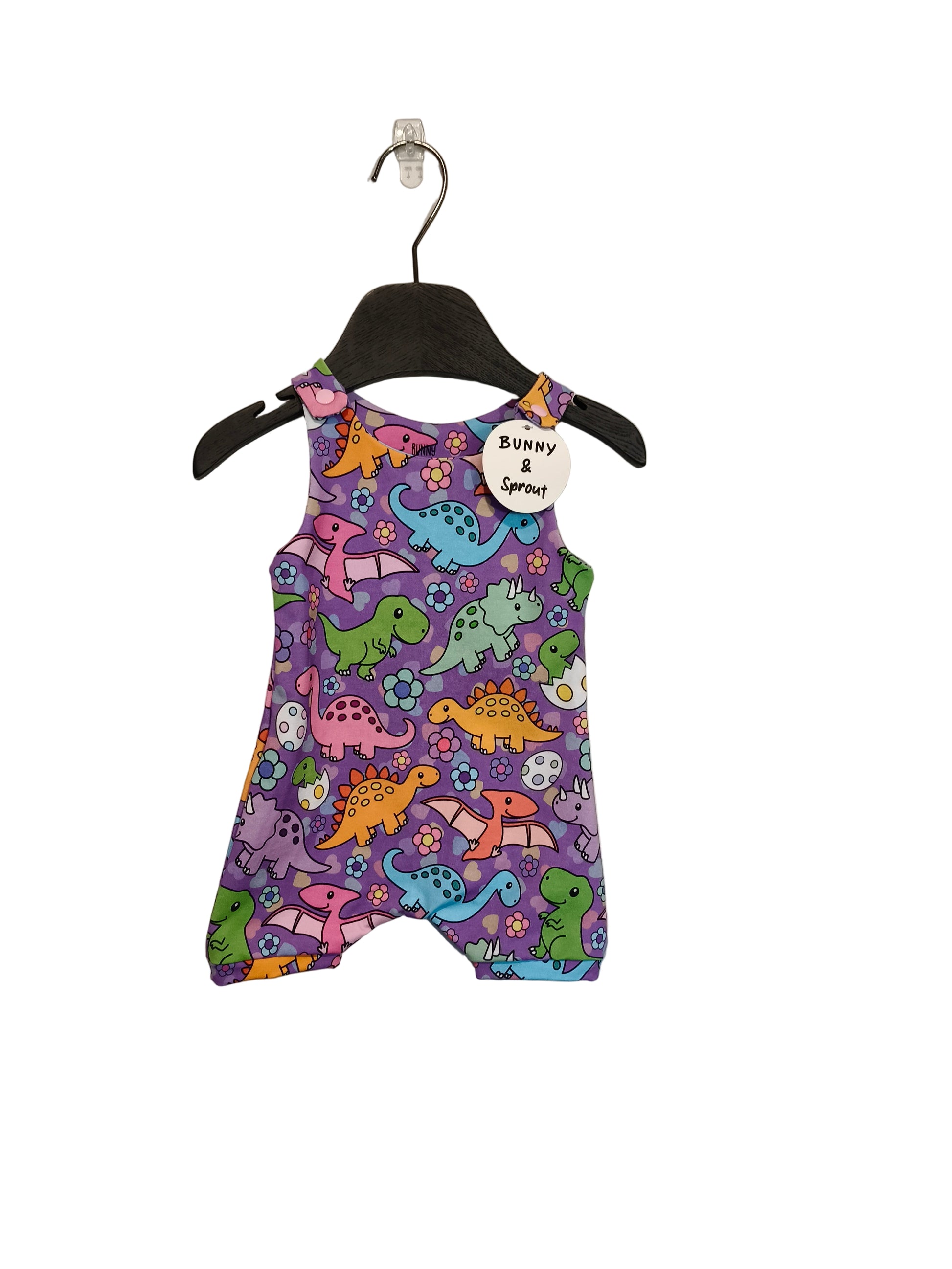 Purple romper with dinosaur pattern on a hanger against a gray background