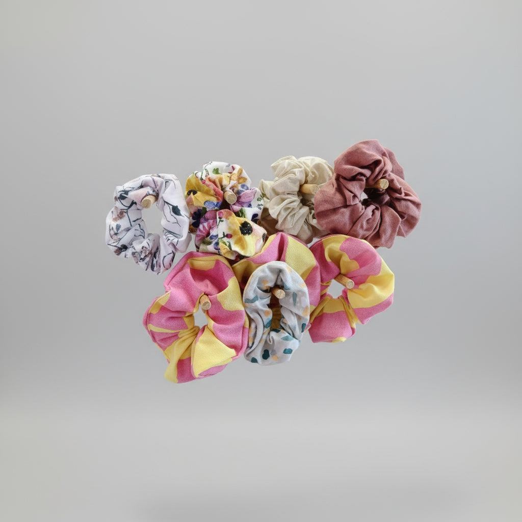 A collection of multicolored scrunchies displayed on a stand, with some in solid colors and others with floral patterns.